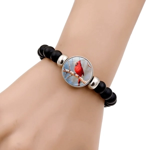 Close-up of black matte beaded bracelet with a cardinal bird charm on a woman's wrist