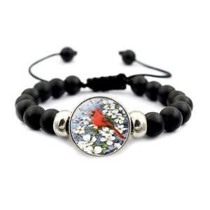 Detail of adjustable beaded bracelet featuring black matte beads and red cardinal bird pendant