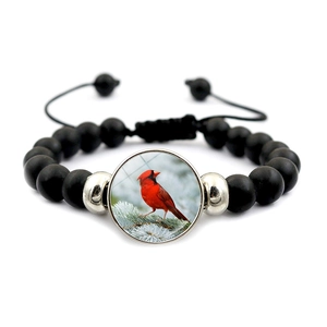 Detail of beaded bracelet featuring matte black beads and red cardinal bird pendant charm