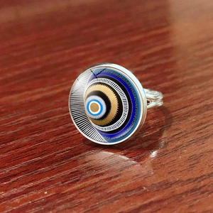 Detail shot of Turkish evil eye open ring with silver band on dark wood texture