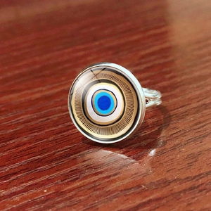 Detailed top view of silver Evil Eye ring with blue glass dome on wood surface
