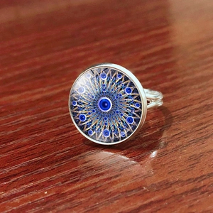 Detailed top view of an adjustable Evil Eye ring with blue mandala glass on a wood surface