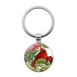 Detail of cardinal bird glass cabochon pendant with silver metal keyring and floral design