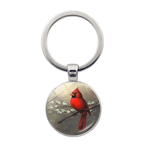 Detail of round silver keychain featuring a red cardinal bird on a branch with flowers