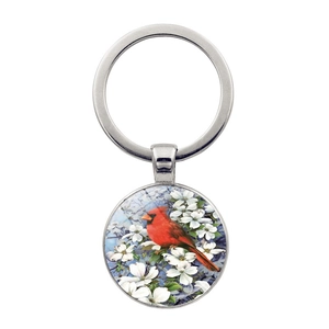 Macro shot of circular keychain featuring a cardinal bird and white flower illustration