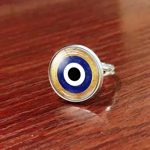 Adjustable silver Evil Eye ring with blue Turkish eye glass set on a rustic wooden table
