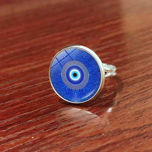 Silver evil eye open ring with blue glass cabochon on a vintage wooden background