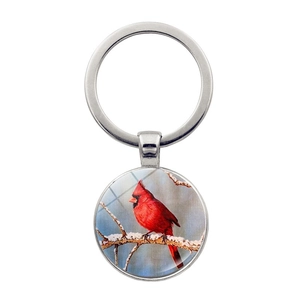 Round silver cardinal bird keychain with realistic winter snow pattern on white background