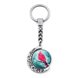Detail of silver cardinal bird keychain with double-sided rotating moon pendant and art illustration
