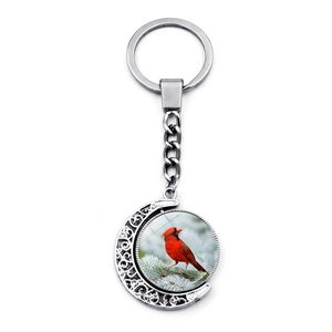 Silver cardinal bird keychain with rotating double-sided glass gem on white background