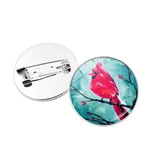 Detail of cardinal bird brooch with glass cabochon and silver metal safety pin back