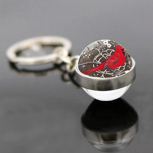 Macro detail of cardinal glass ball keychain showing glossy silver metal base and reflection