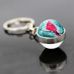 Detail of cardinal bird pendant with silver metal ring and clear glass sphere crystal