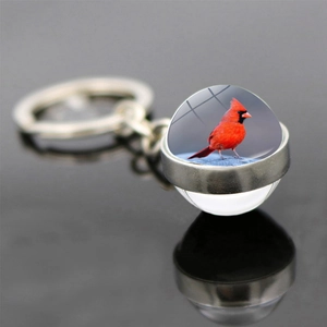 Macro detail of cardinal bird keychain with double-sided glass ball and silver alloy ring
