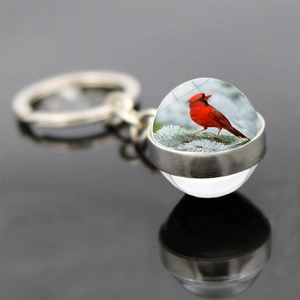 Macro view of double-sided glass ball keychain with vibrant red cardinal bird pattern