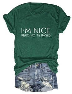 Flat lay of dark green T-shirt with I'M NICE PERO NO TE PASES text and denim shorts