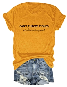 Detail of CAN'T THROW STONES letter print on yellow t-shirt with ripped denim shorts