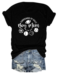 Flat lay of women's black T-shirt with Boy Mom slogan and distressed denim shorts