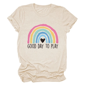 Dettaglio dello slogan 'GOOD DAY TO PLAY' e stampa cuore arcobaleno su t-shirt beige