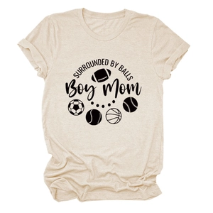 Close-up of beige T-shirt showing SURROUNDED BY BALLS text and various sports icons