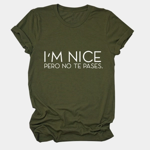 Close-up of olive green t-shirt with I'M NICE PERO NO TE PASES printed text details