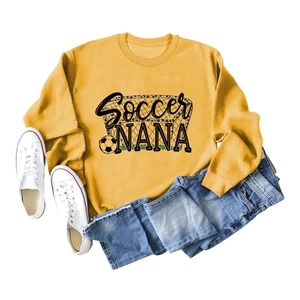 Flat lay of mustard yellow soccer nana sweatshirt with football graphic and denim jeans