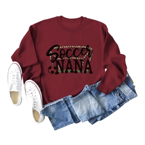 Flat lay of maroon Soccer NANA sweatshirt with leopard print text and white sneakers