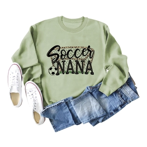 Flat lay of green soccer nana sweatshirt with football graphic and white canvas sneakers