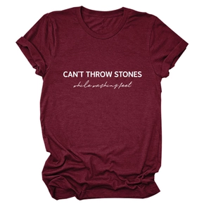 Close-up of burgundy cotton t-shirt with CAN'T THROW STONES white text and folded sleeves