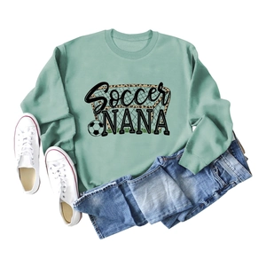 Flat lay of sage green Soccer NANA sweatshirt with ribbed cuffs and blue jeans