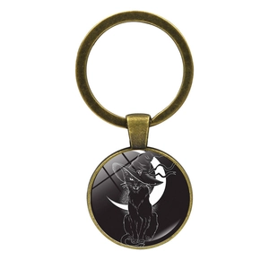 Detail of vintage bronze keychain featuring a black cat with witch hat and crescent moon