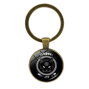 Detail of gothic bronze keychain with mystical black cat and moon phases glass pendant