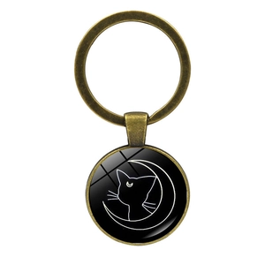 Close-up of bronze cat keychain pendant with glass crescent moon cat graphic detail