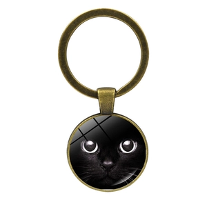 Vintage bronze keychain with black cat eyes glass cabochon pendant on white background