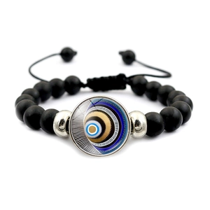 Détail de perles noires mates et breloque Evil Eye sur bracelet tissé ajustable