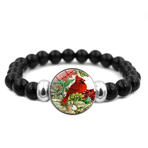 Vista macro del bracciale con perline nere e ciondolo cabochon con uccello cardinale