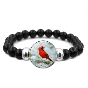 Dettaglio del ciondolo con uccello cardinale su bracciale di perle nere con metallo argento