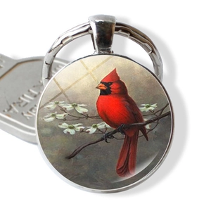 Detailansicht eines Glas-Cabochon Schlüsselanhängers mit Kardinalvogel auf weißen Blüten