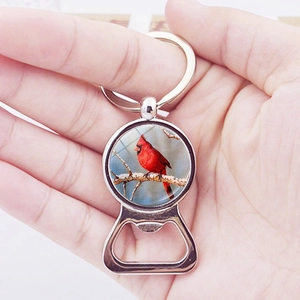 Silver cardinal bird bottle opener keychain with glass dome pendant held in hand