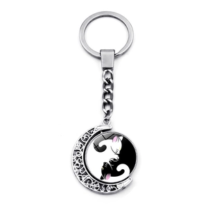 Detail of a rotating metal keychain featuring a crescent frame and cat yin yang pattern