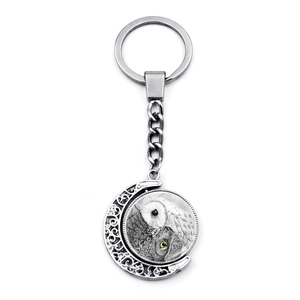 Macro detail of the rotating silver metal pendant with an owl sketch and yellow eyes
