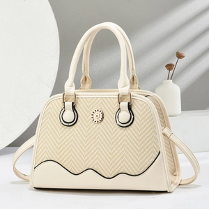 Detail of beige shell bag featuring chevron straw panel and gold hardware accents