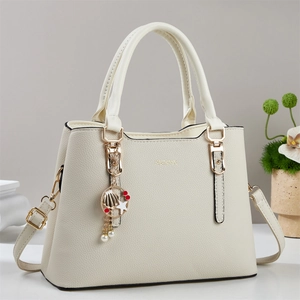 Elegant cream leather tote bag with gold shell charm and adjustable shoulder strap
