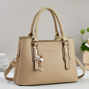 Dettaglio borsa beige in pelle martellata con ciondolo a perla e manico in metallo