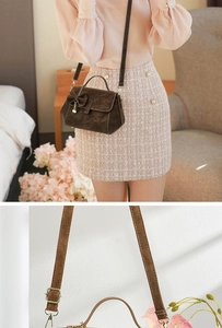 Detail of adjustable shoulder strap stitching and brown faux leather texture on bag