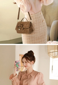Detail of brown faux suede crossbody bag with bow accent and pearl metal charm