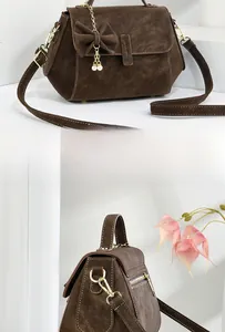 Detail of dark brown faux leather handbag with pearl charm and bow decoration