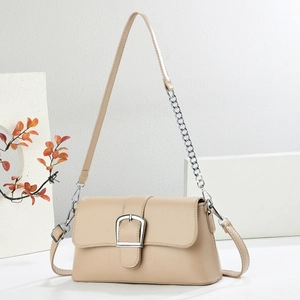 Detail of light beige baguette bag showing silver buckle and chain strap on minimalist stand