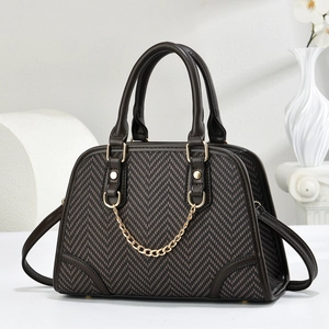 Elegant brown herringbone tote bag with gold chain and leather trim on white pedestal