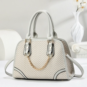 Detail of grey leather and beige woven fabric tote with elegant gold chain accessory